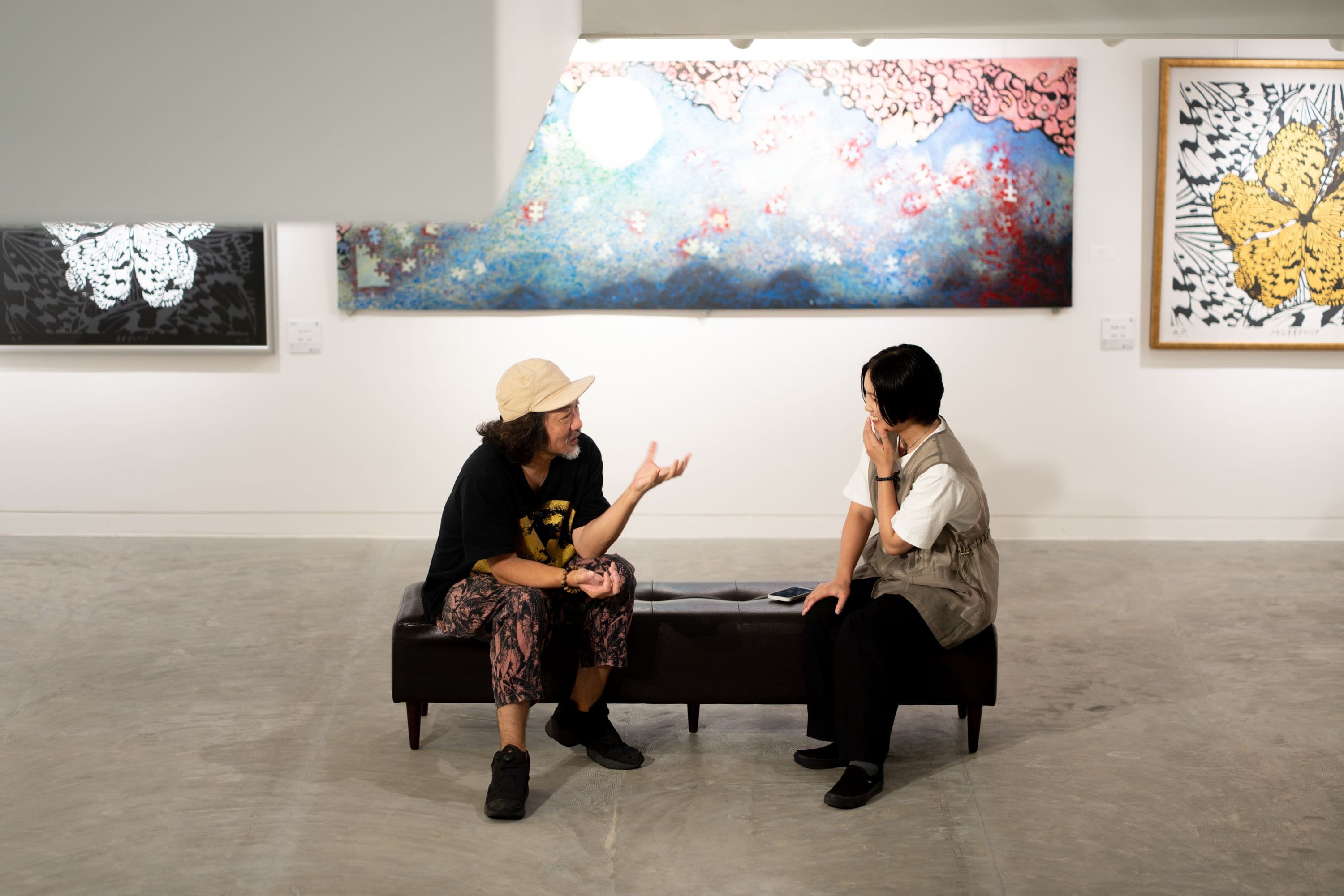 イチグスクガロウの展示室で、ベンチに座って話す池城安武さんと村上あす美さん