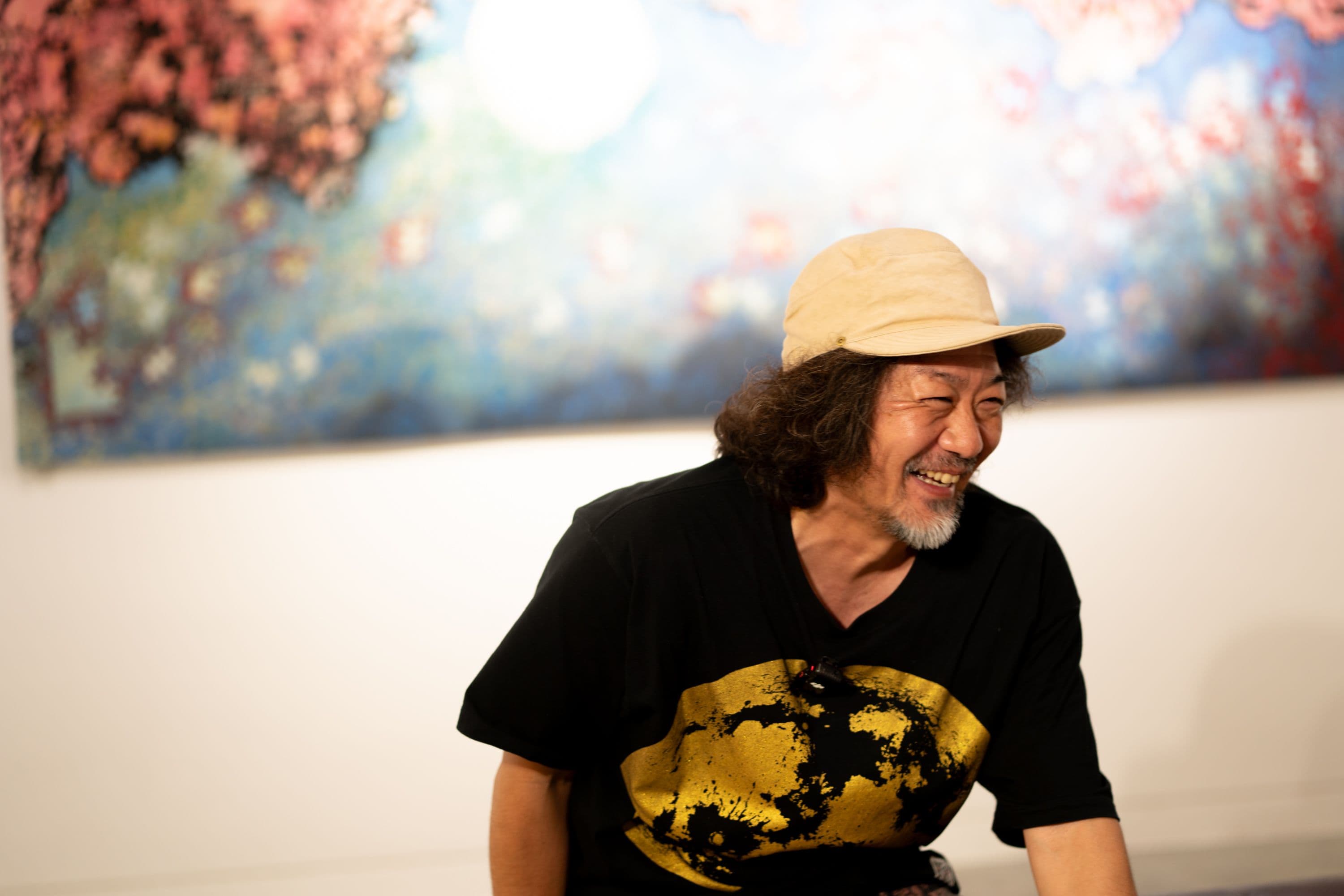 ギャラリーの作品の前で笑顔を見せる池城安武さん