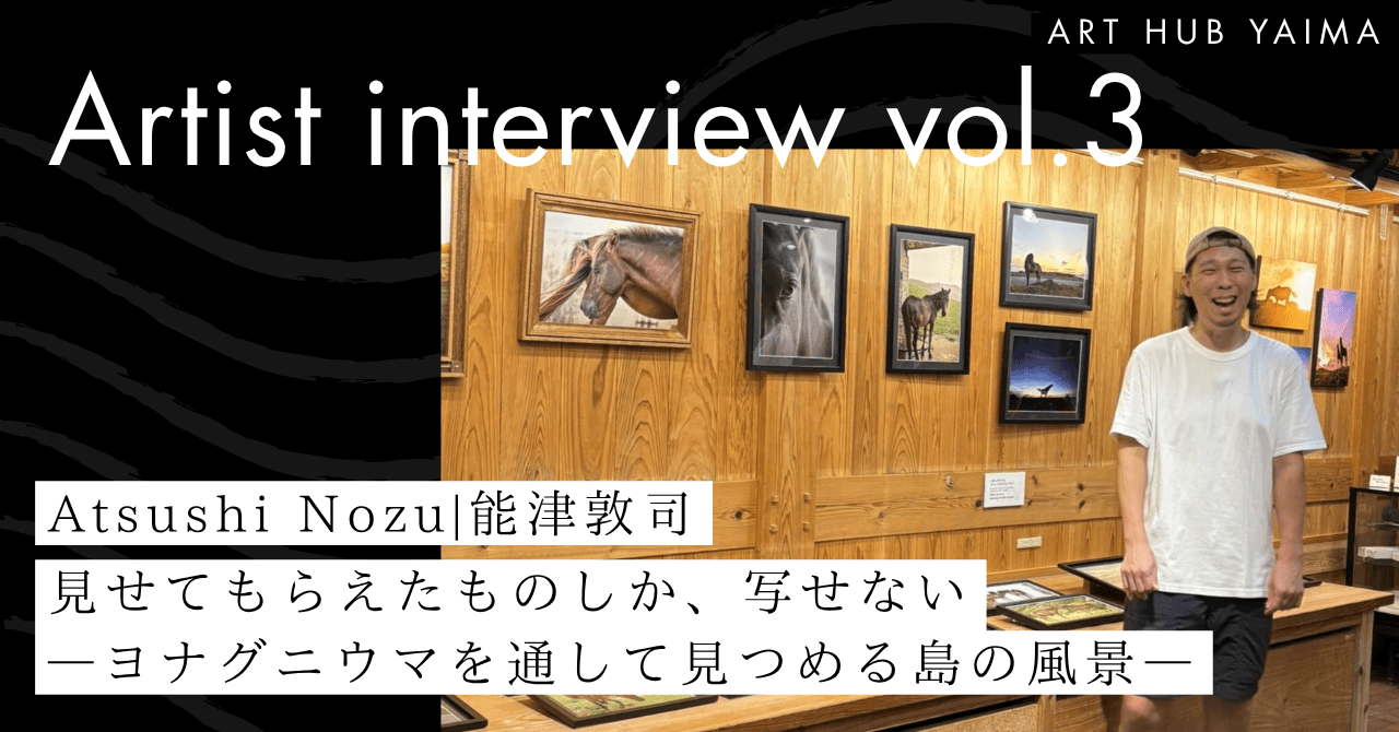 ART HUB YAIMA「Artist interview vol.3 能津敦司」のタイトル画像。木の壁にヨナグニウマの写真作品が並ぶギャラリーに立つ能津敦司さんと、記事タイトルが記されている